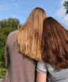 two girls sitting beside each other with hair showing